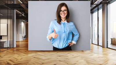 smiling businesswoman with thumb up over gray background Wall mural