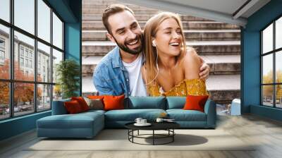 Smiling lovely young couple sitting together on stairs Wall mural