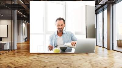 Smiling mature man having tasty breakfast Wall mural