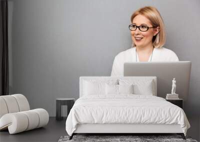 Smiling middle-aged blonde woman in shirt and eyeglasses Wall mural