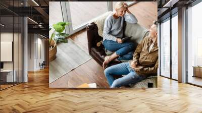 Smiling middle aged white couple relaxing on a couch Wall mural