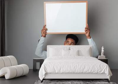 Smiling young african man holding blank board above his head Wall mural