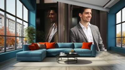 smiling young businessman standing at the glass doors Wall mural