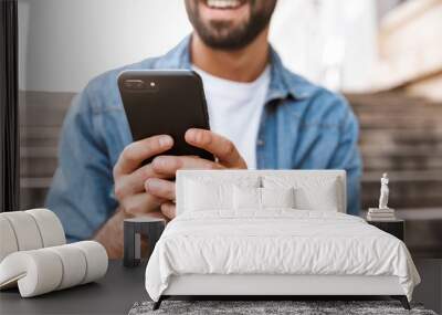 Smiling young man using mobile phone Wall mural