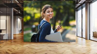 Smiling young teenage girl carrying backpack walking Wall mural