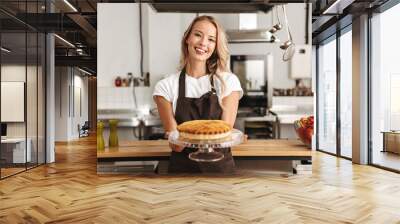 Smiling young woman chef cook in apron Wall mural