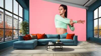 Sports fitness woman isolated over pink wall background make stretching exercises. Wall mural