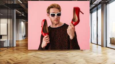 Stylish young white man gay showing high heel red shoes Wall mural