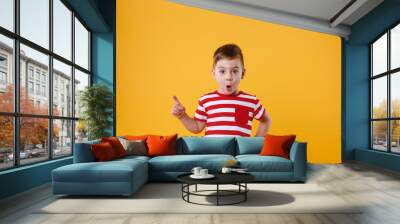 Surprised little boy standing and pointing finger away Wall mural