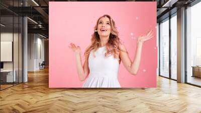 Surprised young woman over confetti. Looking aside. Wall mural