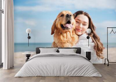 tender smiling young woman hugging her dog on the beach Wall mural