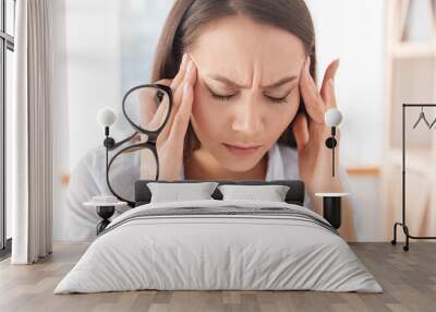 Tired businesswoman massaging her head Wall mural