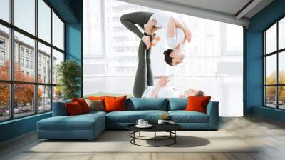 Two beautiful young women stretching and practicing acro yoga exercises Wall mural