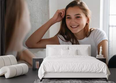 Two cheerful girls talking while sitting at home Wall mural