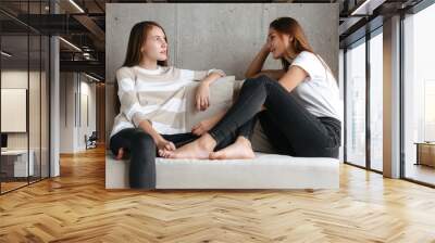 Two cheerful girls talking while sitting at home Wall mural