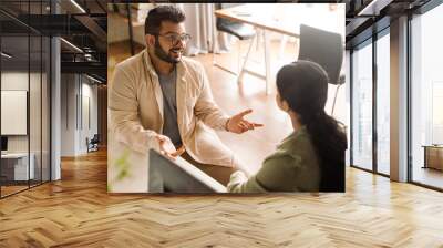 Two coworkers discussing business details while sitting in modern office space Wall mural