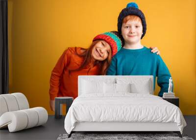 two happy little children wearing warm hats. Wall mural