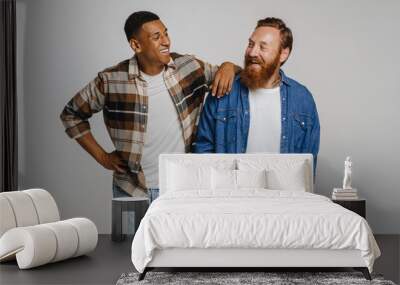 Two happy men smiling and posing at camera while standing isolated Wall mural