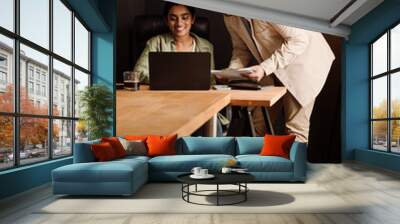 Two indian coworkers using laptop while working together in office Wall mural