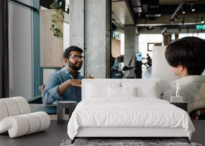 Two male colleagues talking while working together in office Wall mural