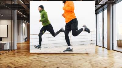 Two motivated young sportsmen jogging outdoors Wall mural