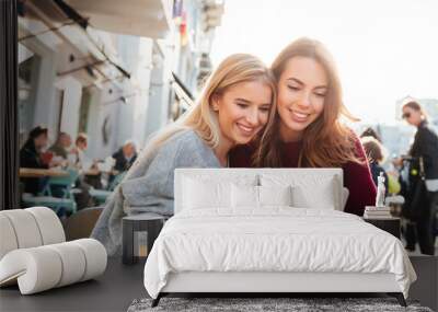 two smiling young girls watching video on mobile phone Wall mural