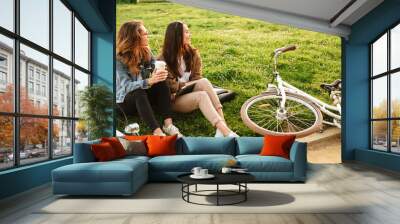 Two young beautiful women friends outdoors with bicycles Wall mural