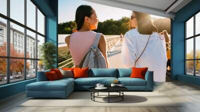 View from back on two beautiful young stylish smiling girls Wall mural