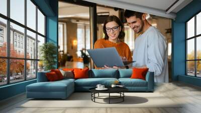 White colleagues discussing project while working with laptop in office Wall mural