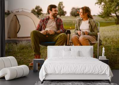 White couple smiling and drinking tea during camping together Wall mural