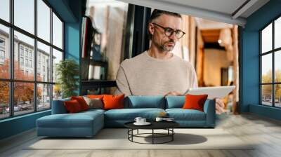 White middle-aged man using tablet computer while working in office Wall mural