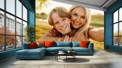 White mother and son smiling while taking selfie photo on field Wall mural