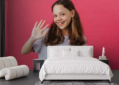 White preteen girl wearing t-shirt smiling and waving hand Wall mural