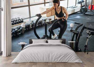 Woman athlete training on bicycle in gym Wall mural