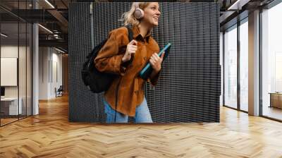 Woman in headphones smiling while walking through city street Wall mural