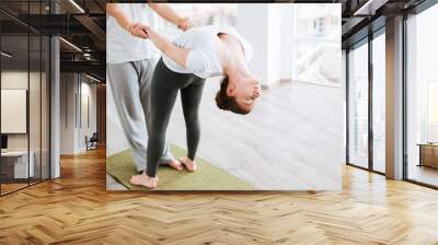 Woman stretching and doing acro yoga with partner in studio Wall mural