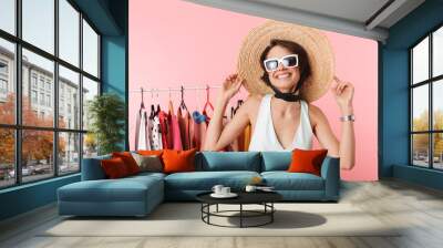 woman stylist posing isolated over pink wall background near a lot of clothes. Wall mural