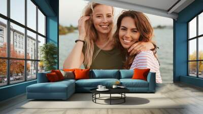 Women friends hugging outdoors on the beach. Wall mural