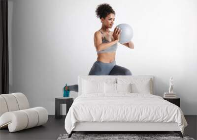 Young amazing sports fitness african woman posing isolated over white background make exercises with ball. Wall mural