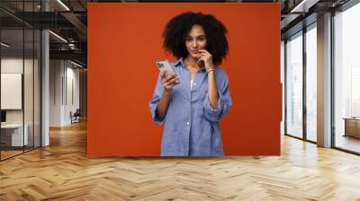 Young beautiful curly thoughtful woman in blue shirt with phone Wall mural