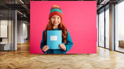 Young beautiful girl showing blue copy book and smiling isolated Wall mural