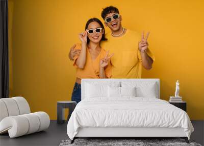 Young beautiful happy couple in sun glasses showing victory gesture Wall mural