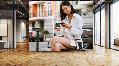 Young beautiful smiling asian woman with coffee and phone Wall mural