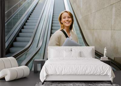 Young beautiful smiling business lady in blazer holding laptop Wall mural