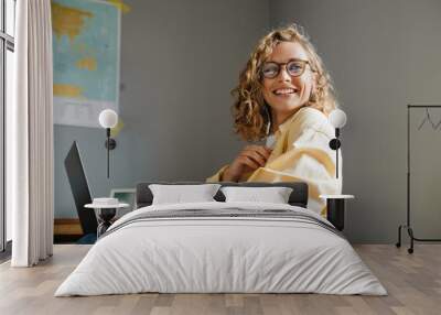 Young beautiful smiling woman in glasses with laptop looking aside Wall mural