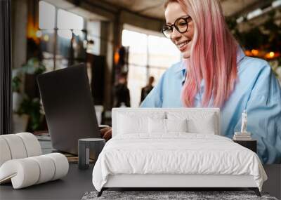 Young beautiful woman smiling and using laptop in cafe Wall mural