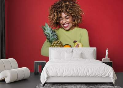 Young black woman laughing while posing with fruits Wall mural