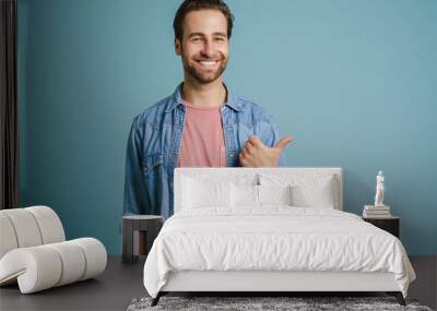 Young bristle man wearing shirt smiling and pointing finger aside Wall mural