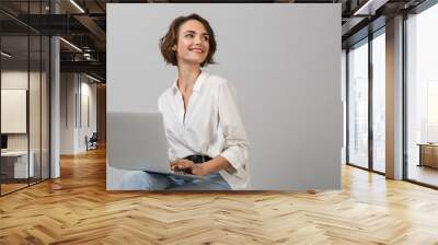 Young business woman posing isolated over grey wall background sitting on stool using laptop computer. Wall mural