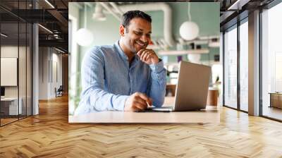 Young businessman in formal wear using laptop while working at office Wall mural